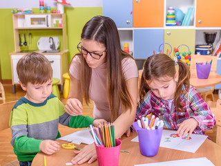 Naklejka premium Preschool Kids Drawing With Teacher