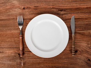 Empty plate rustic fork and knife on wooden table