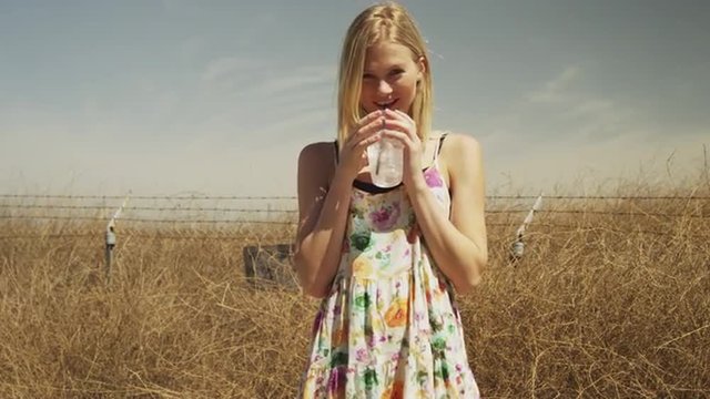Young blonde woman smiling at camera with drink