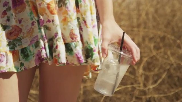 Closeup of a woman holding an iced drink outdoors