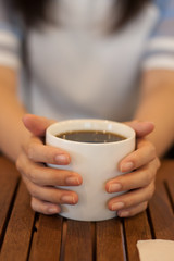 Woman holding white mug on wood table in coffee shop