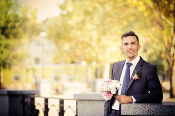 Groom holding wedding bouquet outdoors