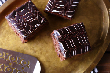 Sweet chocolate cakes and spatula on tray with stripped cotton serviette, close up