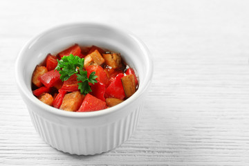 Tasty vegetarian ratatouille made of eggplants, squash, tomatoes in bowl on wooden table background
