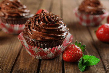 Chocolate cupcakes and strawberries on wooden background