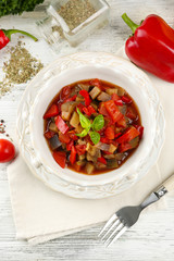Ratatouille in bowl, on wooden table background