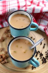 Mugs of soup on wooden mat closeup