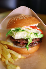 Sandwich and french fried potatoes in craft paper on a table