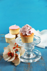 Tasty cupcakes on stand, on color wooden background