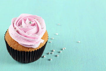 Tasty cupcake on color wooden background