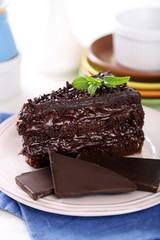 Chocolate cake with chocolate cream on plate, on light background
