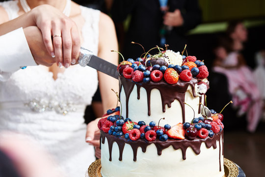 Cutting the wedding cake with berries