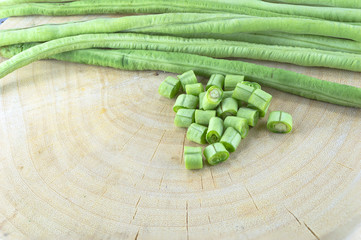 Fresh beans on wooden chopping board with one of the beans slice