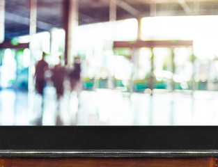 Empty black marble table top and blurred people in building corr