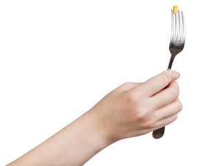 hand holding fork with impaled yellow corn seed