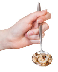 female hand holds spoon with mess of pottage