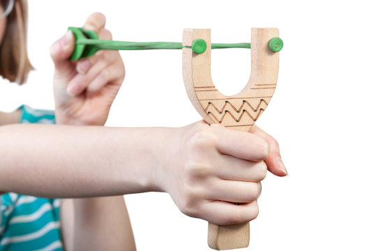 girl pulls green rubber band of wooden slingshot