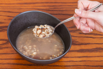 hand holds tablespoon with beans soup over bowl