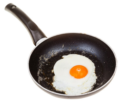 one fried egg in black frypan isolated on white