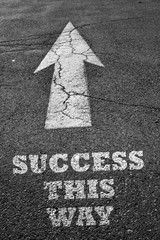 Arrow sign on asphalt surface with success word