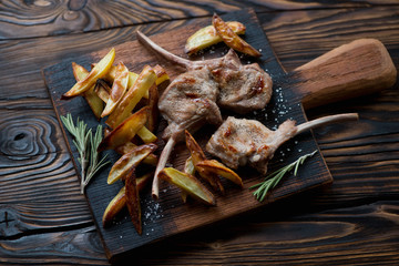 Chopping board with grilled bobby veal rack steaks and fries