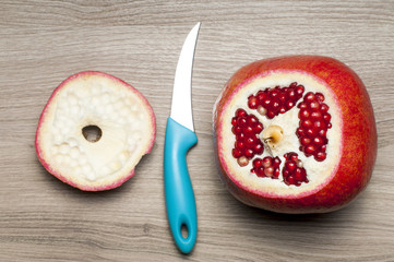 The cut-off top of the pomegranate and the knife on the table.