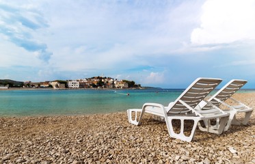Two white deckchairs on a beautiful beach in Croatia