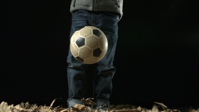 Child playing socceball on black background shooting with high speed camera, phantom flex.