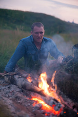  man sitting   near bonfire