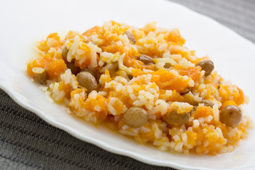 Pumpkin rice porridge with raisins close-up on white plate. 