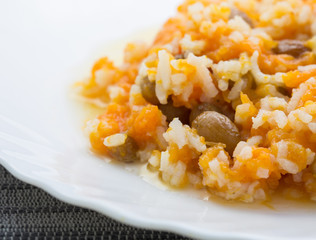 Pumpkin rice porridge with raisins close-up on white plate. 