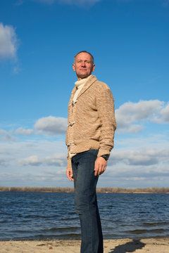 Smiling man, wearing casually, walking along the coast , looking