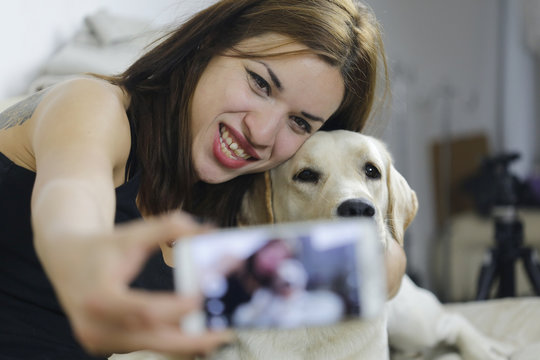Young Caucasian girl taking a selfie with labrador dog at home