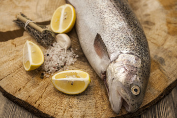 Fresh Norwegian rainbow trout with lemon and onions on a wooden background