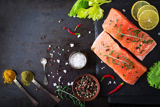 Raw salmon fillet and ingredients for cooking on a dark background in a rustic style. Top view