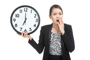 Sleepy young Asian business woman with a clock in the morning