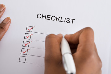 Person's Hand Marking Check Box With Red Pen