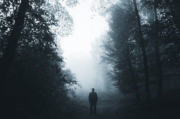 man silhouette in dark foggy forest