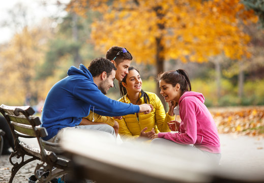  The group of friends, invigorated from their jog, find a park bench to relax, sharing laughter and stories as they enjoy the pleasant autumn day.