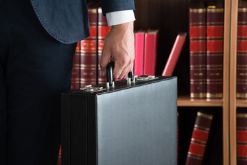 Lawyer Carrying Briefcase Against Bookshelf