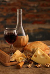 A glass of wine, hard, aged cheese and nuts..