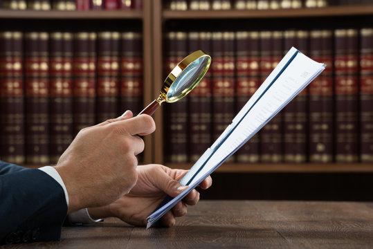 Lawyer Examining Documents With Magnifying Glass