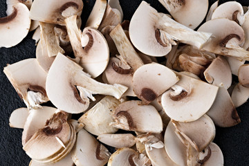 Cut champignon mushroom on the surface of dark stone.