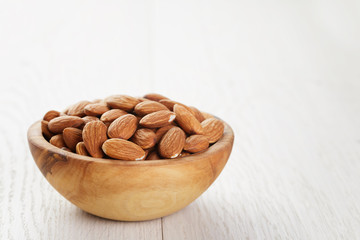 olive bowl full of almonds on wood table
