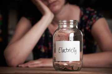 Depressed Woman Looking At Jar Labelled Electricity