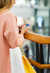 close up of woman with smartphone and shopping bag