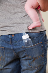 Back View Of Father Carrying Baby With Bottle In Pocket