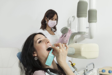 Dentist prepares to make tooth x-ray image for girl in dental cl