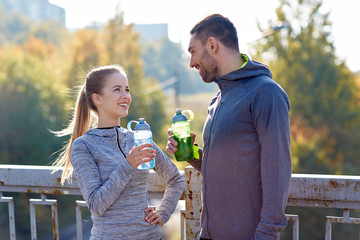 smiling couple with bottles of water outdoors