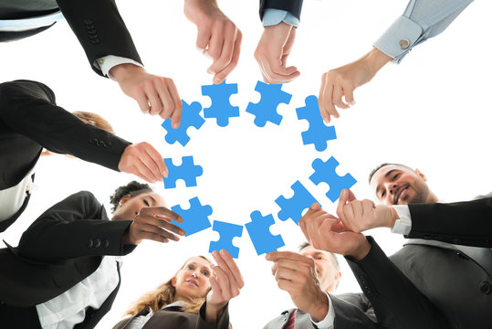 Business Team Joining Jigsaw Pieces In Huddle